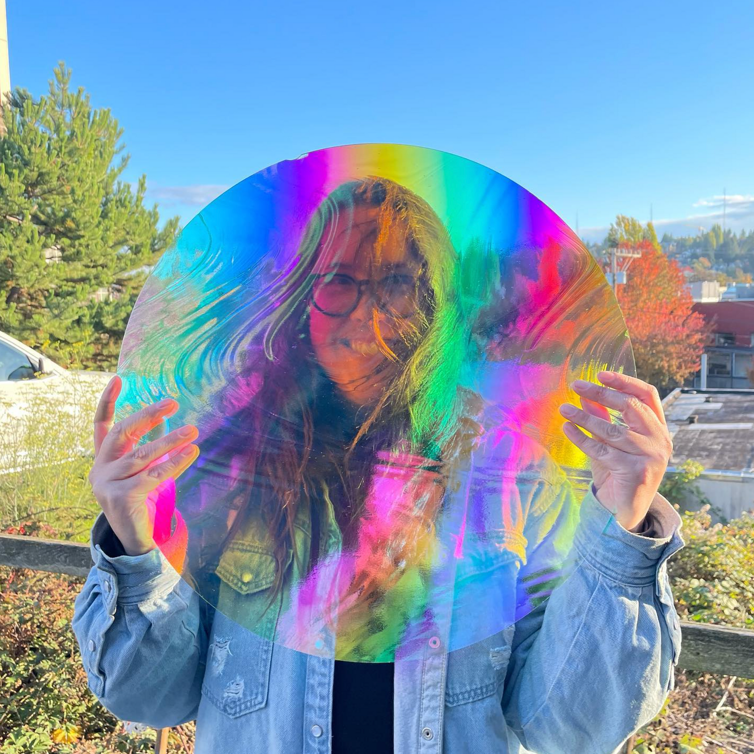 Stained glass artist Korina Oswald holding a piece of rainbow stained glass